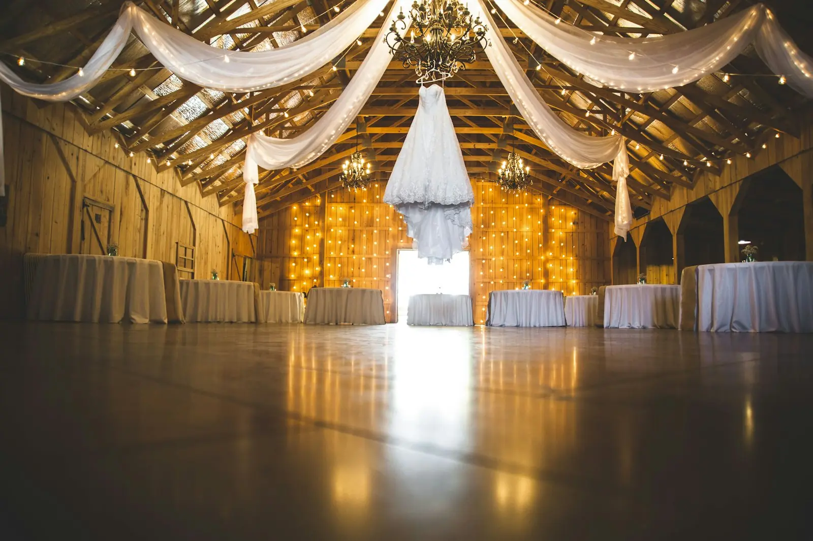 Candlelit barn wedding reception with draped fabric and a chandelier