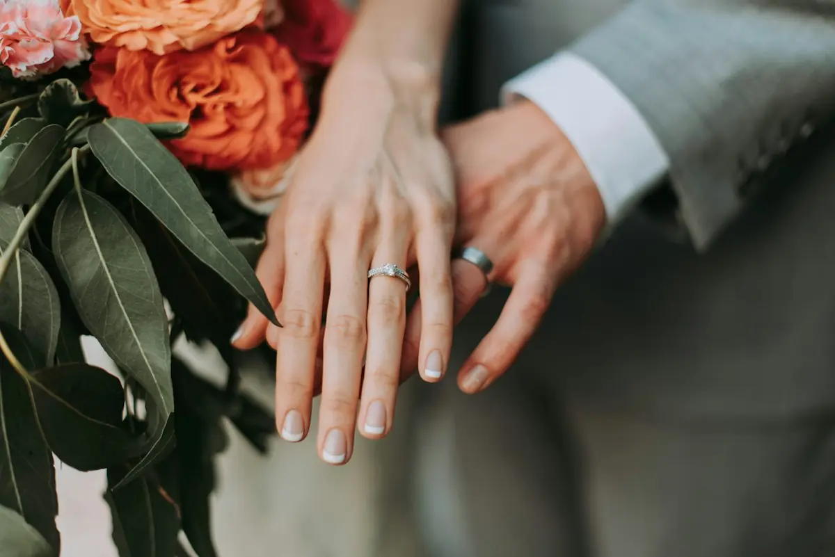 The couple's hands with new wedding rings among green leaves
