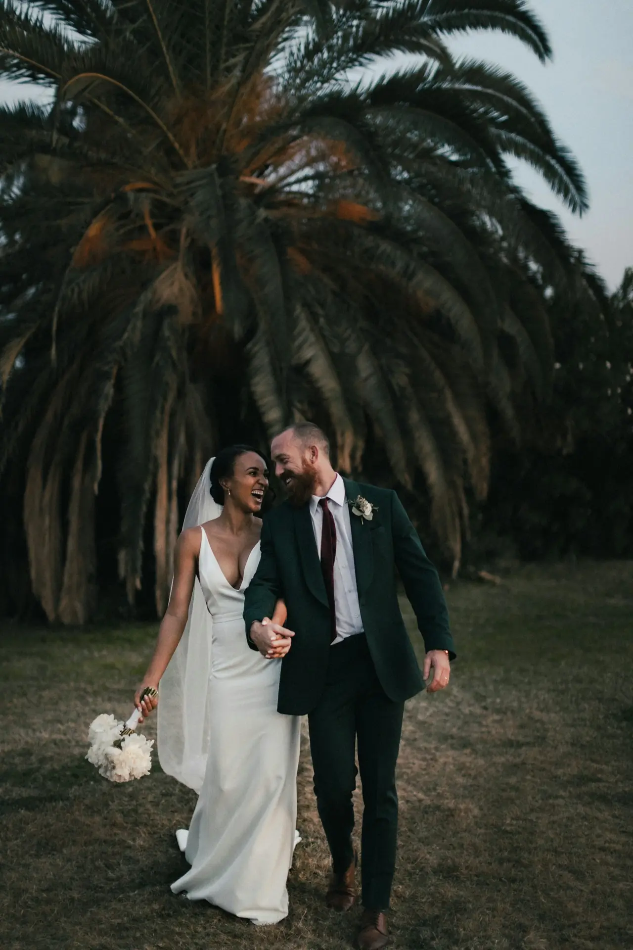 Bride and groom laughing together under the trees